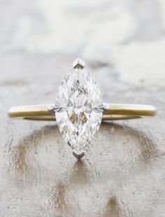 a pear shaped diamond sits on top of a stone surface in front of the camera