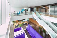 the interior of an office building with purple and white furniture, glass balconies, and stairs