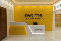 a yellow and white reception area with the name realme on it's wall