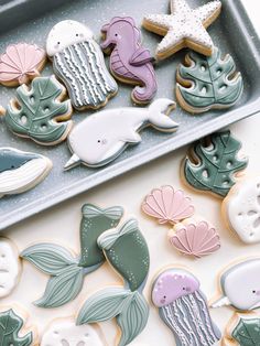 decorated cookies in the shape of sea animals and seashells on a cookie sheet