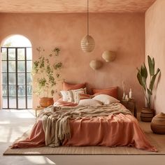 a bedroom with pink walls and an arch leading to the patio area, along with a bed covered in blankets and throw pillows