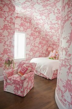 a bedroom with pink and white wallpaper, two chairs and a bed in the corner