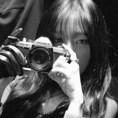 black and white photograph of a woman holding up a camera