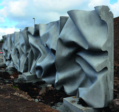 a row of stone sculptures sitting next to each other on top of a dirt field