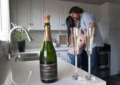 a couple kissing in the kitchen next to two champagne flutes