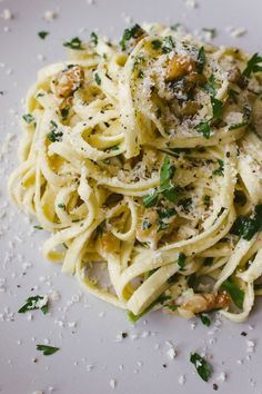 a white plate topped with pasta covered in parmesan cheese and garnished with herbs