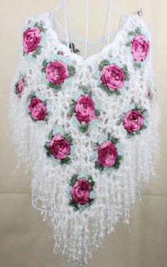 a crocheted white shawl with pink flowers on it