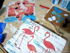 three flamingos are painted on wood with watercolors and paintbrushes next to them