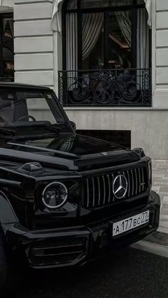 a black mercedes g - class parked in front of a building