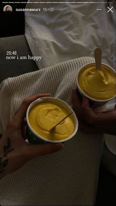 two people holding cups with yellow food in them