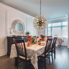 the dining room table is set with flowers and fruit on it, along with an elegant chandelier