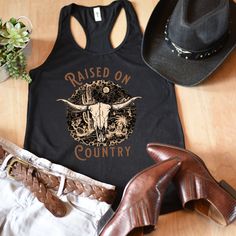 Show your inner cowgirl in this cute country cow skull tank. A great tank top while rockin' out at your favorite country concert. An awesome gift for your best friend or favorite country girl. All of our tank tops are printed on the Next Level 1533 racerback tank. This racerback cut looks good on any woman's shoulders. It's soft and comfortable and is made from 60% combed ring-spun cotton, 40% polyester. The fabric has a subtle luxurious feel, making it pleasant to touch. Made from specially spu Country Tank Tops Women, Black Western Tops For Summer, Black Western Style Summer Tops, Black Western Style Tops For Summer, Summer Tank Top With Skull Print, Western Style Fitted Sleeveless Tank Top, Fitted Western Style Sleeveless Tank Top, Fitted Sleeveless Western Tank Top, Fitted Country Style Tops For Country Events