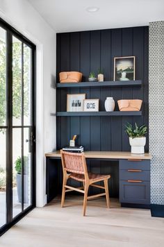 a desk and chair in a room with dark wood paneling on the walls, along with potted plants