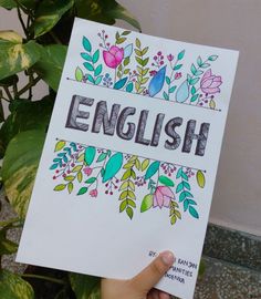 a person holding up a sign that says english with flowers and leaves on the front