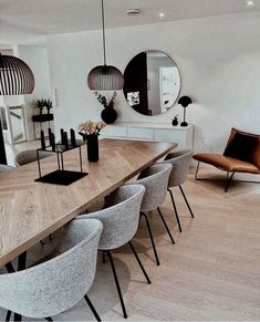 a large wooden table surrounded by chairs in a living room with mirrors on the wall