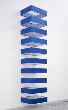 an abstract sculpture made out of blue strips on a white wall in the middle of a room