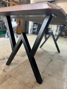 a wooden bench sitting on top of a tile floor next to a metal frame structure