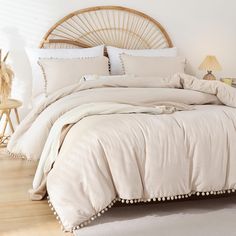 the bed is made with white linens and pom poms