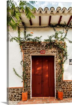 a red door in front of a white building with ivy growing on it's side