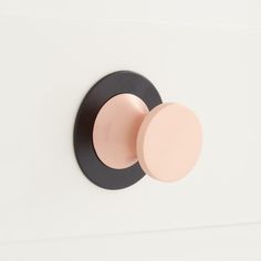 a black and pink knob on a white wall