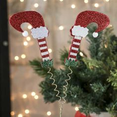 a small christmas tree in a vase with santa's hats on it and lights behind