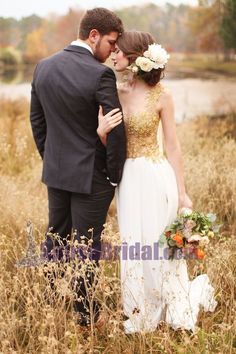 a bride and groom are standing in the tall grass with their arms around each other