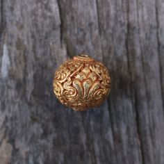 a gold colored object sitting on top of a wooden table next to a piece of wood