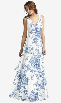 a woman in a white and blue dress with flowers on the skirt is looking down at her