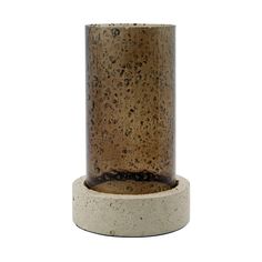 a brown and white vase sitting on top of a cement stand with a black base