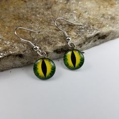 two green and yellow earrings on top of a rock