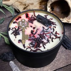 a bowl filled with white and red flowers next to a skeleton key on top of a wooden table