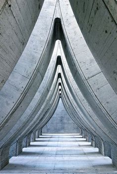 black and white photograph of the inside of a building with curved concrete pillars in it