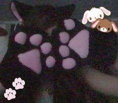 a person wearing a black vest with pink paw prints and a dog on it's chest