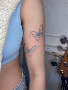 a woman with a butterfly tattoo on her right arm and left arm behind her is a guitar