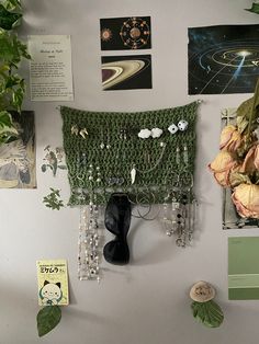 a wall covered in pictures and plants next to a vase with some flowers on it