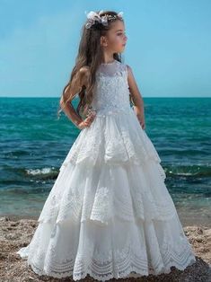 Say YES to this stunning girls' ball gown for Communion Day! Your lil' empress will adore the full,  tiered lace skirt ending in a beautiful train, and sheer bodice covered with enchanting flowers in front and back. Give her the dress of her dreams today! She can move and play confidently even after formal events and i Dressy Gowns, Girls Ball Gown, Special Occasion Gowns, Princess Flower Girl Dresses, First Communion Dress, First Communion Dresses, Girls Couture, White Flower Girl Dresses, Tiered Maxi Skirt