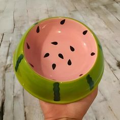 a hand holding a green and pink watermelon bowl