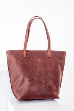 The most eye-catching tote ever! Exclusive orchid hot embossing at leather tote. DETAILS: * Antique grain leather. * One roomy zipped compartment. * Soft and sturdy cotton lining. * Author's orchid hot embossing . COMPARTMENTS AND POCKETS: * External jetted pocket with zip on the bag's back side; * Inside: - jetted pocked with zip; - patch pocket with zip; - mini compartment between two pockets above; - simple patch pocket. Fits lots of stuff and laptop up to 13'', sport shoes and bottle of wate Embossed Tote Bag For Travel, Embossed Leather Shoulder Bag, Embossed Travel Shoulder Bag, Embossed Satchel Shoulder Bag For Everyday Use, Leather Satchel Bag With Embossed Details, Embossed Leather Bag With Double Handle, Embossed Bags With Double Handle For Daily Use, Embossed Double Handle Bag For Daily Use, Leather Double Handle Embossed Bag