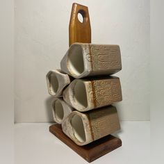 a stack of three ceramic vases sitting on top of a wooden stand next to a white wall