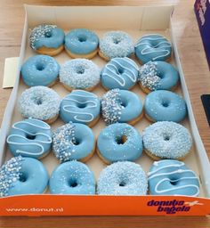 a box filled with blue frosted donuts covered in sprinkles on top of a wooden table