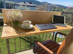 a laptop computer sitting on top of a wooden desk next to a cup of coffee