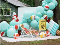 a woman laying on a beach chair surrounded by blue and red balloons in front of a house