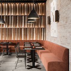 a restaurant with brick walls and wooden booths, tables and chairs in front of them