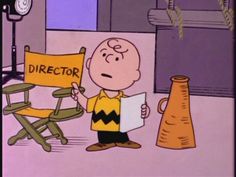 a cartoon character holding up a director's sign in front of a yellow chair