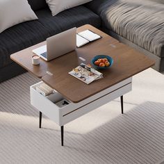 a coffee table with a bowl of fruit on it and a laptop in the middle