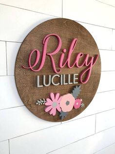 a wooden sign that says riley lucile with flowers and leaves on the side of it