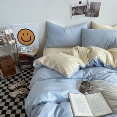 an unmade bed with blue sheets and pillows on top of it, next to a black and white checkered floor