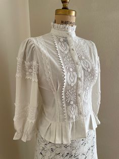 "This is a gorgeous vintage women's white 3/4 sleeve victorian boho style cotton blouse with lace crochet & lace detailing, puffed shoulders, and a unique hem... stunning! My guess is that it's from the 70s or 90s fashioned in a 1970s style but I'm not exactly sure. These are new old stock or deadstock, I have a limited amount of these; they were from a theater company that closed in the 90s. This has a button-down bodice, high neck collar, slight silver subtle stripe, and 3/4 length sleeves. Pe Blouse Puff Sleeve, Victorian Boho, Edwardian Blouse, Blouse Crochet, Victorian Blouse, White Cotton Blouse, Lace Trim Blouse, Mode Boho, Boho Blouse