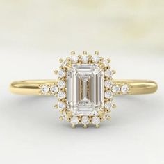 an emerald - cut diamond engagement ring set in yellow gold