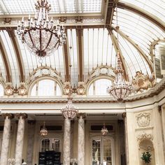 the inside of a building with chandeliers hanging from the ceiling and marble columns